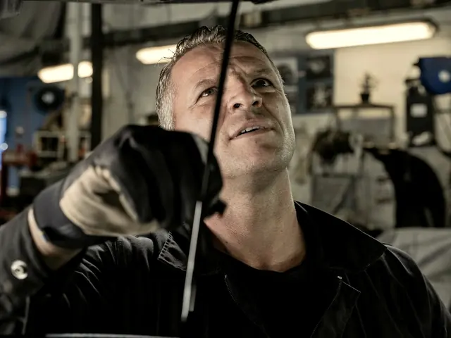 Mechanic looking up at the underside of a car on a lift