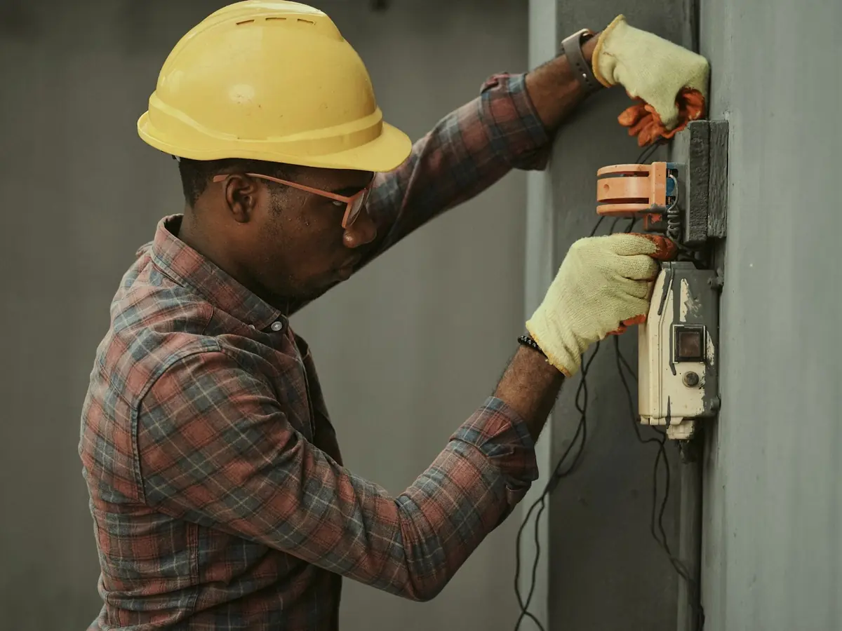 Electrician in a hard hat testing a wall meter