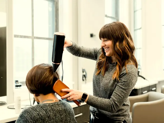 Stylist smiling as she blow-dries a client’s hair